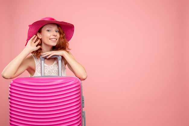 Front view of female tourist with pink bag on pink wall