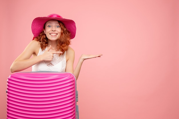 Front view of female tourist with pink bag on pink wall