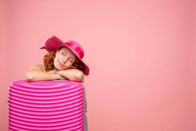 Front view of female tourist with pink bag sleeping on pink wall