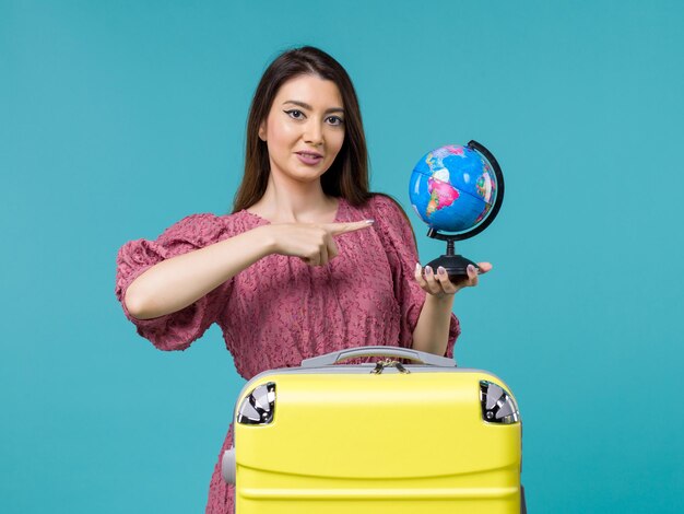 Front view female in trip holding globe on blue background journey trip vacation voyage woman sea