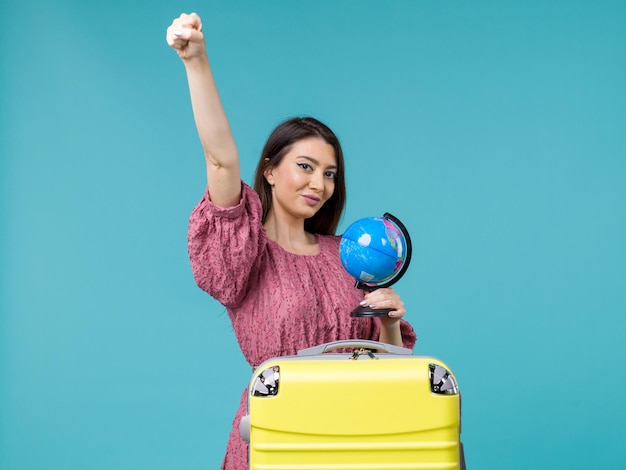 Front view female in trip holding little globe on a blue background journey trip vacation voyage woman sea