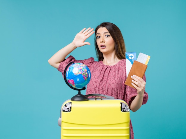 Donna di vista frontale nel portafoglio della tenuta di viaggio con i biglietti sul viaggio di vacanza di viaggio della donna di viaggio del mare del fondo blu