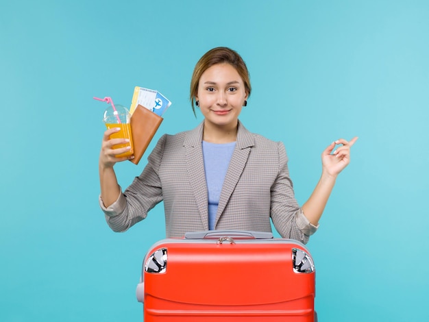 Front view female in vacation holding drink and tickets on blue background sea trip vacation plane voyage travelling