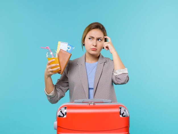 Front view female in vacation holding drink and tickets on the blue background sea trip vacation voyage travelling