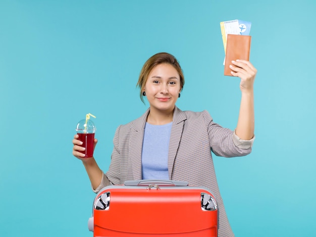 Femmina di vista frontale in vacanza che tiene succo di ciliegia fresco e biglietti sullo sfondo blu viaggio viaggio aereo vacanza viaggio