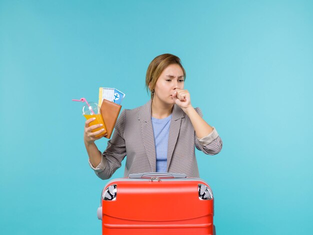 Front view female in vacation holding fresh drink and tickets coughing on blue background sea trip vacation voyage travelling