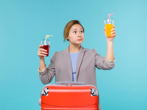 Front view female in vacation holding fresh drinks on a blue background trip voyage vacation travel sea plane