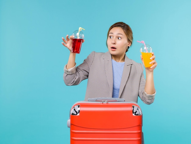 Front view female in vacation holding fresh drinks on light blue background sea trip vacation plane voyage travelling