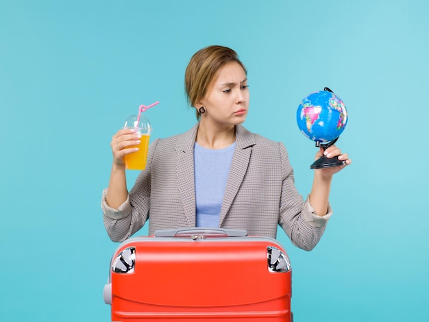 Front view female in vacation holding fresh juice and globe on blue background sea vacation voyage journey trip