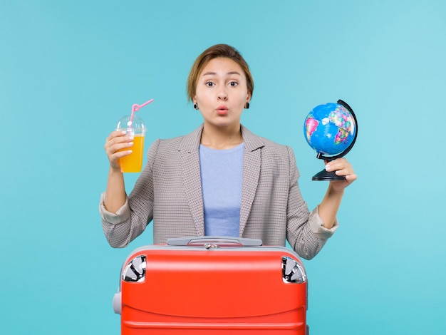 Front view female in vacation holding fresh juice and globe on the blue background sea vacation voyage journey trip