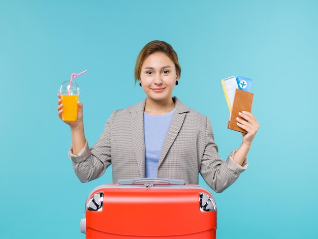 Front view female in vacation holding fresh juice and tickets on a blue background sea vacation plane voyage trip journey