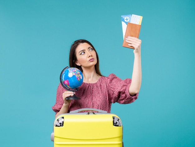 Front view female in vacation holding globe and plane tickets on a blue background sea vacation woman trip journey summer