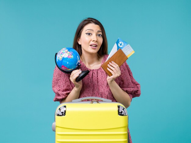 Front view female in vacation holding globe and plane tickets on blue desk sea vacation woman trip journey summer