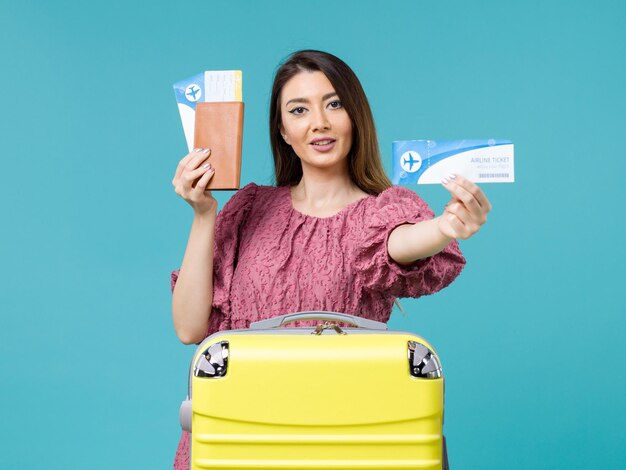 Вид спереди женщина в отпуске, держа билеты на синем фоне, путешествие на море, отпуск, женщина, лето