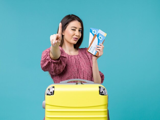 Front view female in vacation holding her tickets on the blue background journey summer trip woman sea human