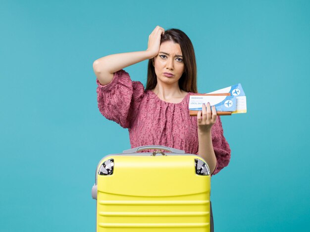 Вид спереди женщина в отпуске, держа билеты на синем фоне, путешествие, летнее путешествие, женщина, отпуск на море