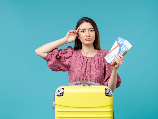 青い机の旅の夏の旅行の女性の海の休暇で彼女のチケットを保持している休暇中の正面図の女性