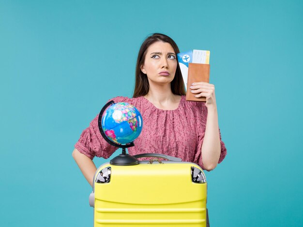 青い背景の海の旅の休暇の女性の旅の航海で彼女の財布とチケットを保持している休暇中の女性の正面図