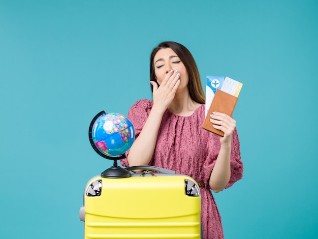 青い背景の海の旅の休暇の女性の旅の航海で彼女の財布とチケットあくびを保持している休暇中の女性の正面図