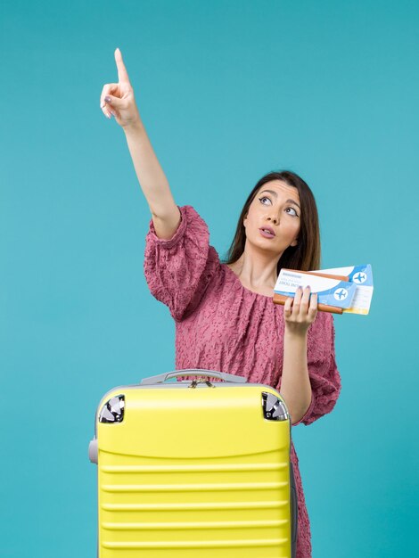 彼女の財布と青い背景の旅の夏の旅行の女性の海の休暇のチケットを保持している休暇中の女性の正面図