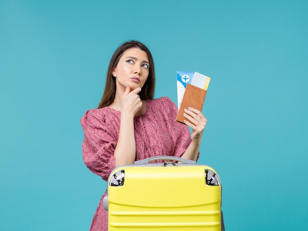 彼女の財布と青い背景の旅の旅行休暇の女性の夏の海のチケットを保持している休暇中の女性の正面図