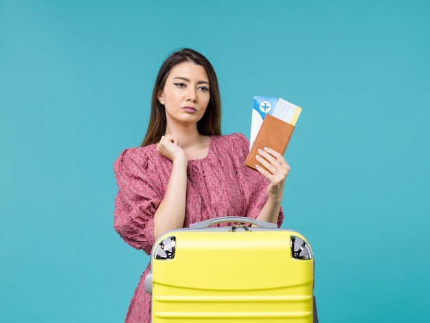 Donna di vista frontale in vacanza che tiene il suo portafoglio e biglietti sul mare di estate della donna di viaggio di vacanza di sfondo blu