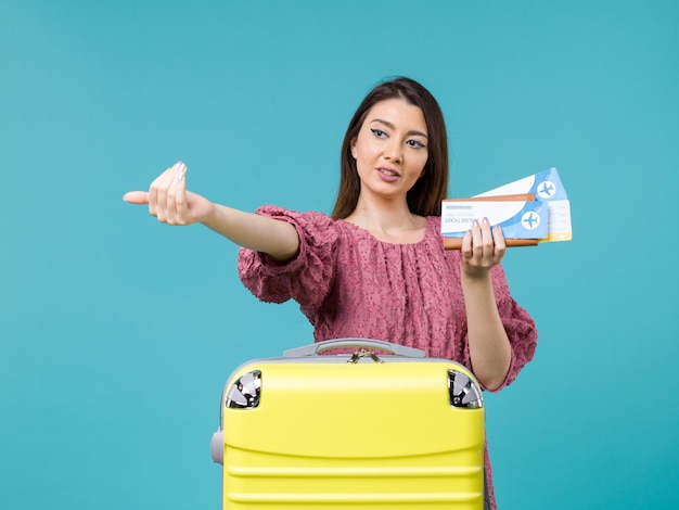 Вид спереди женщина в отпуске, держа свой кошелек и билеты на синем фоне поездка женщина летнее путешествие морские каникулы