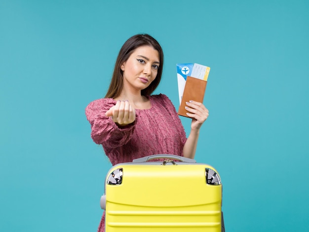 彼女の財布と青い背景の旅の旅の女性の夏の海の休暇で誰かを呼び出すチケットを保持している休暇中の正面図の女性