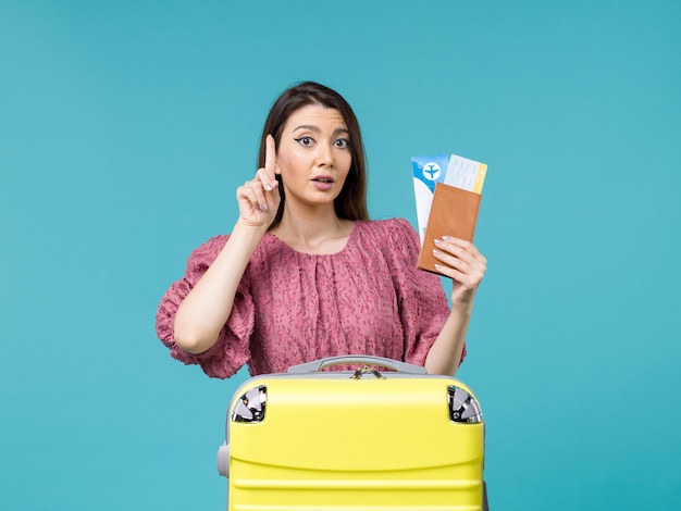 Front view female in vacation holding her wallet and tickets on light blue background journey vacation trip woman summer sea