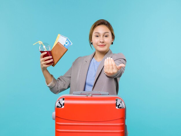 青い床の航海休暇旅行旅行飛行機でジュースとチケットを保持している休暇中の女性の正面図