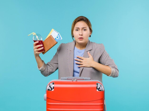 青い背景の旅行航海休暇旅行水上飛行機で咳をするチケットとジュースを保持している休暇中の女性の正面図