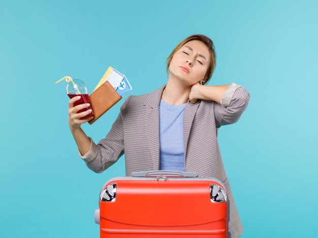 青い背景の旅行航海休暇旅行水上飛行機で首の痛みを持っているチケットとジュースを保持している休暇中の女性の正面図