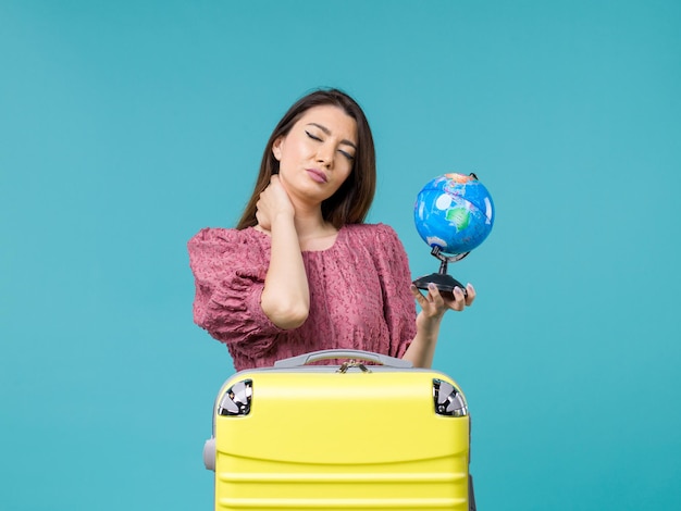青い背景の旅海の女性旅行休暇夏に小さな地球を保持している休暇中の女性の正面図
