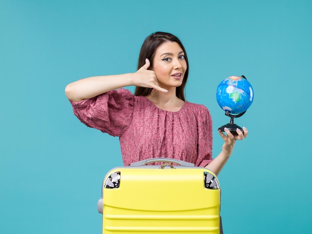 Вид спереди женщина в отпуске, держащая маленький земной шар на синем фоне, морское путешествие, женщина, путешествие, отпуск, лето