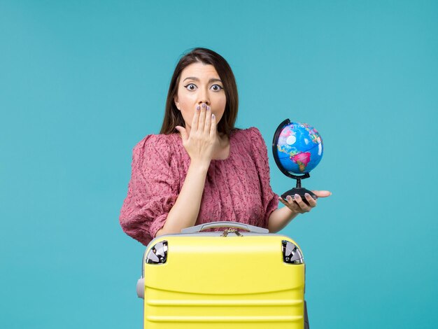 Front view female in vacation holding little earth globe on blue background sea vacation journey summer woman trip