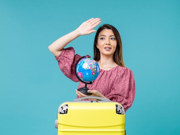 Вид спереди женщина в отпуске держит маленький земной шар на синем фоне море отпуск женщина поездка путешествие лето