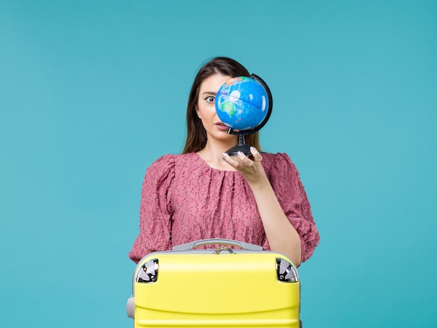 Foto gratuita donna di vista frontale in vacanza che tiene piccolo globo terrestre su fondo azzurro viaggio di vacanza di mare viaggio estivo donna