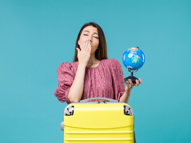Front view female in vacation holding little earth globe and yawning on blue background journey sea woman trip vacation summer