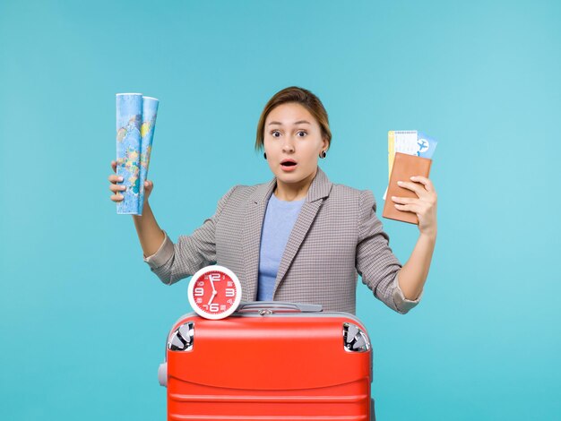 Front view female in vacation holding map and tickets on a blue background plane voyage journey trip vacation sea travel