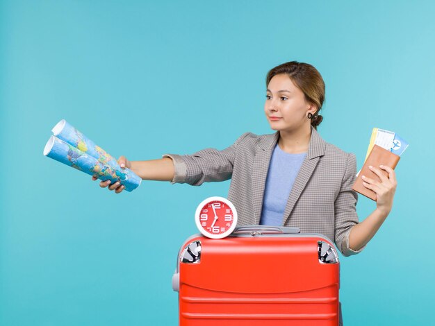 青い背景の飛行機の航海海旅行旅行休暇の地図とチケットを保持している休暇中の女性の正面図