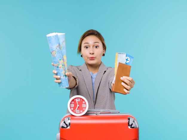 青い床の飛行機の航海の海の旅行旅行の休暇の地図とチケットを保持している休暇中の女性の正面図