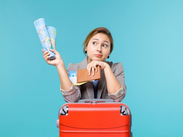 Front view female in vacation holding map wallet and tickets on light-blue background plane voyage sea travel trip vacation