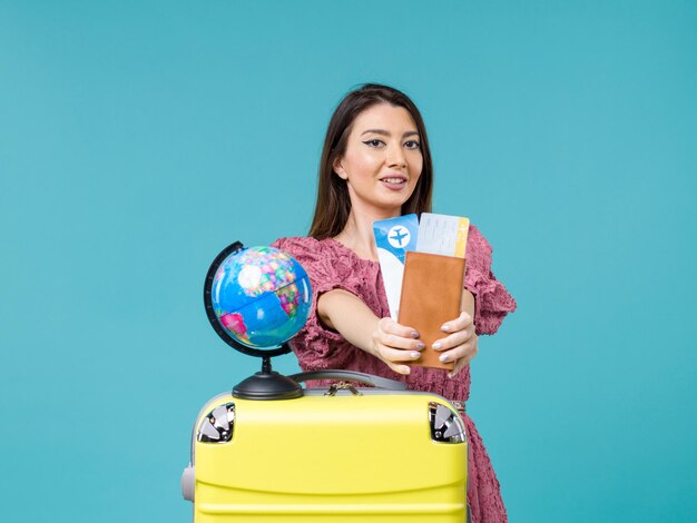 Front view female in vacation holding plane tickets on a blue background sea vacation woman trip journey summer