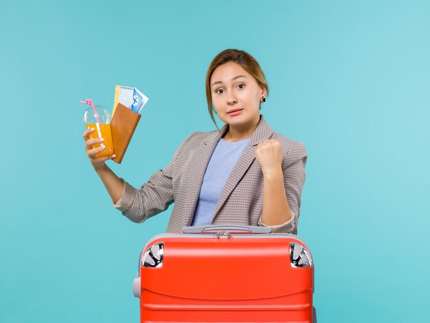 青い背景の飛行機の旅の航海の海の旅のチケットを保持している休暇中の女性の正面図