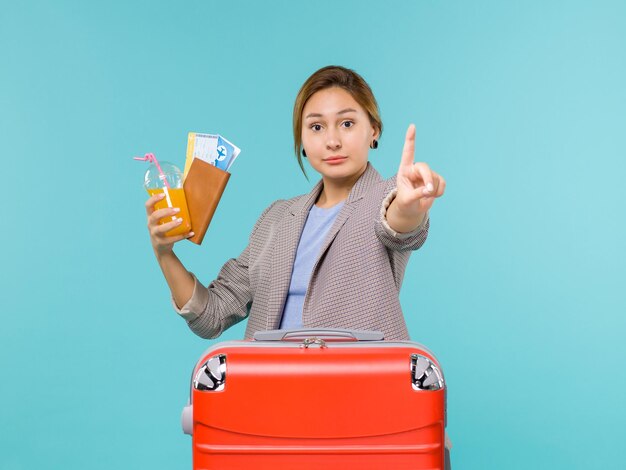 Front view female in vacation holding tickets on blue desk plane journey voyage sea trip