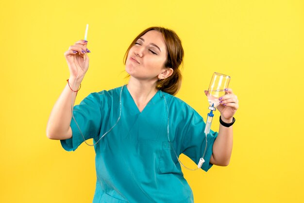 Front view of female veterinarian holding dropper on yellow wall