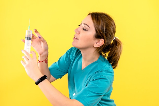 Вид спереди ветеринара-женщины, держащего инъекцию на желтой стене