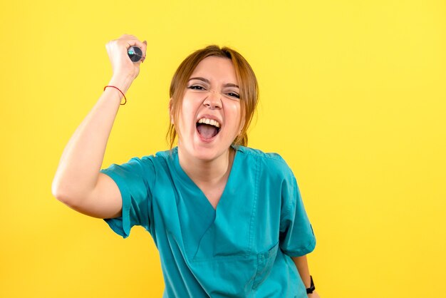 Front view of female veterinarian holding injection on yellow wall