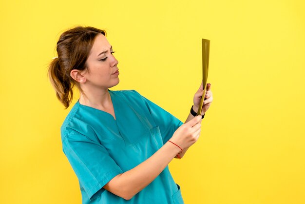 Front view of female veterinarian holding x-ray on a yellow wall