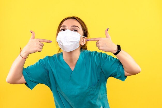 Front view of female veterinarian wearing mask on a yellow wall